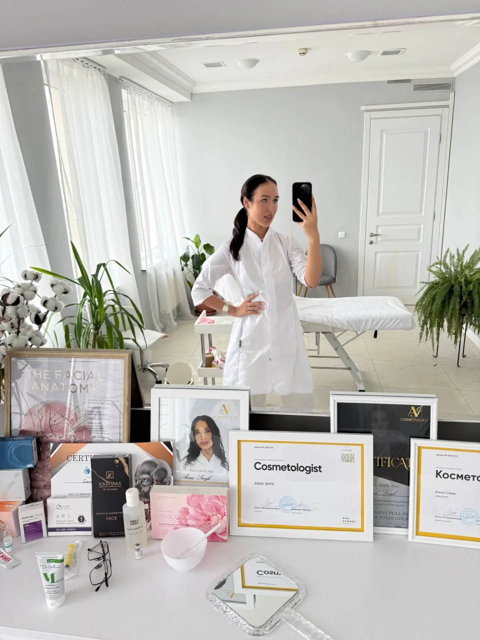 Косметолог Анна у своєму кабінеті поруч із професійними сертифікатами